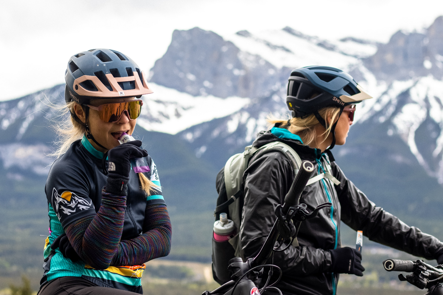 A couple of mountain bikers enjoying a 7 Summits Snacks chocolate energy bar.